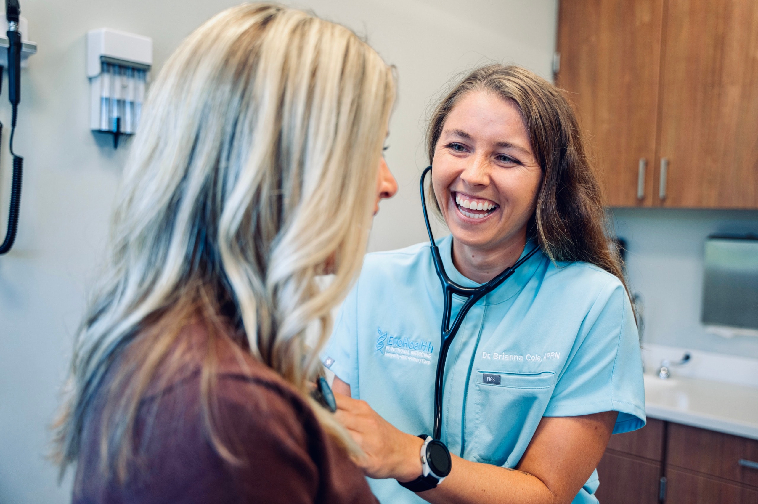 Brianna Cole, DNP, APRN, FNP-C examining a patient with a stethoscope at EvoHealth in Overland Park