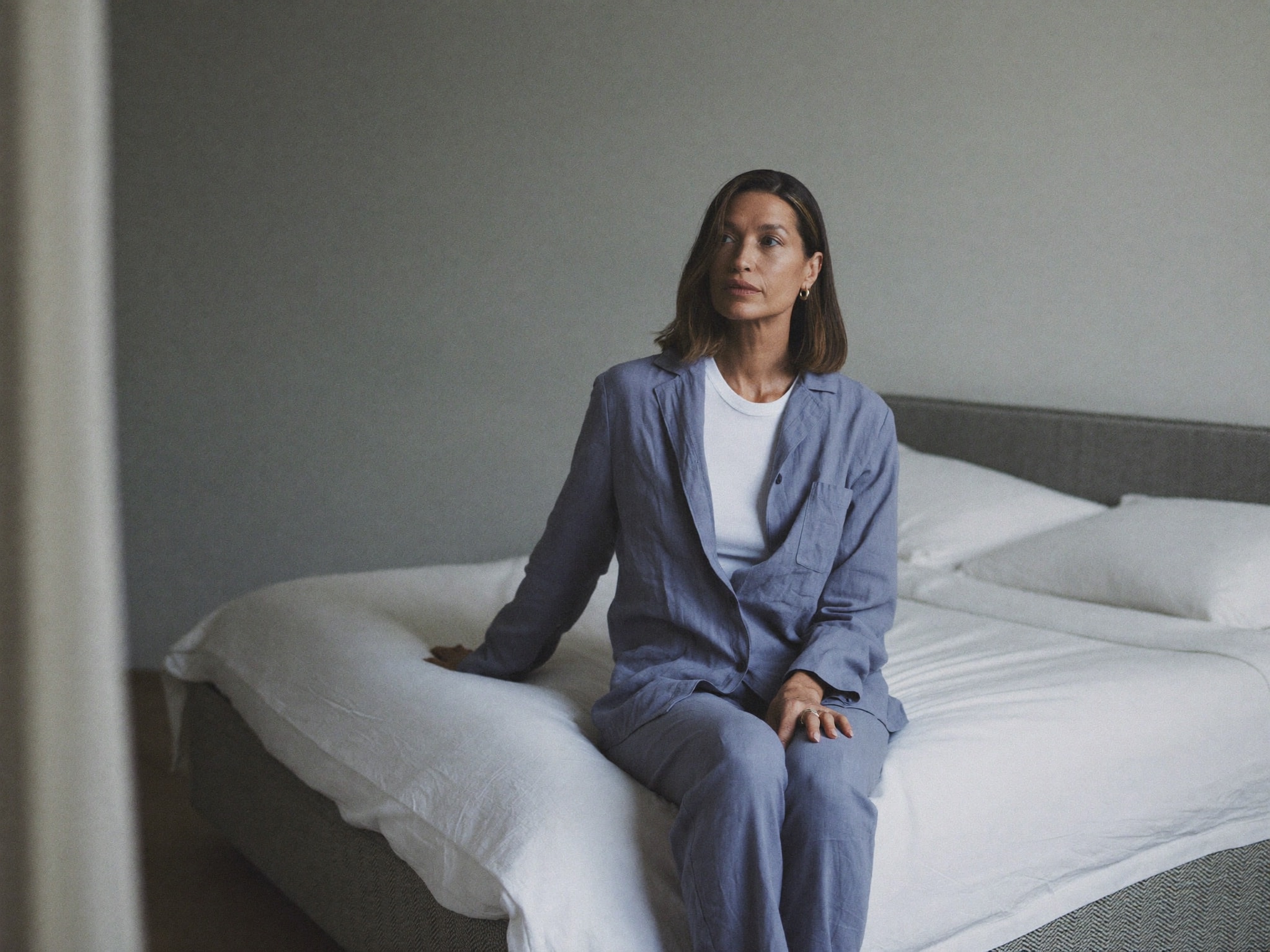 Woman sitting on the edge of a bed in early-morning light