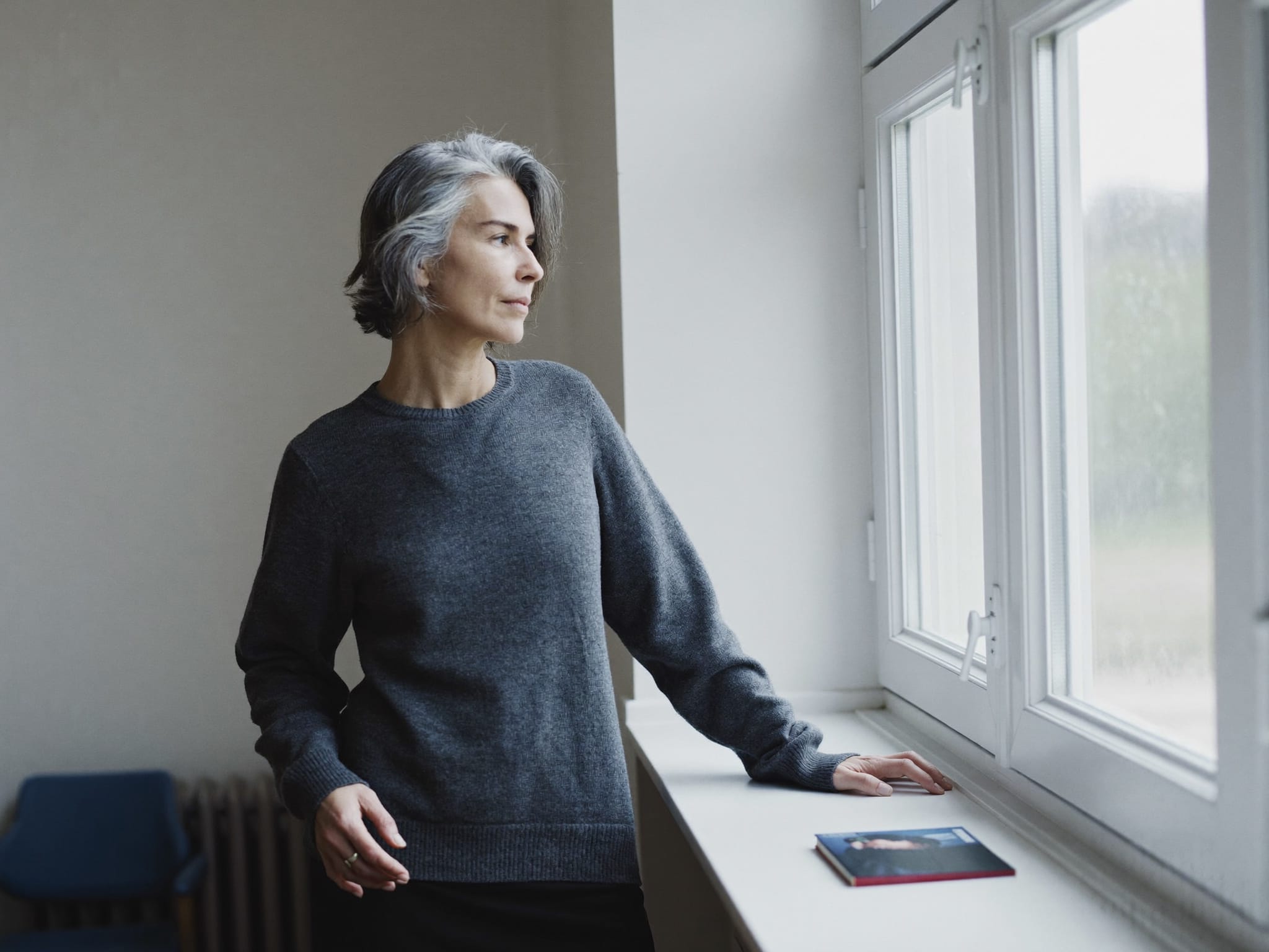 Woman standing by a bright window in a minimal room